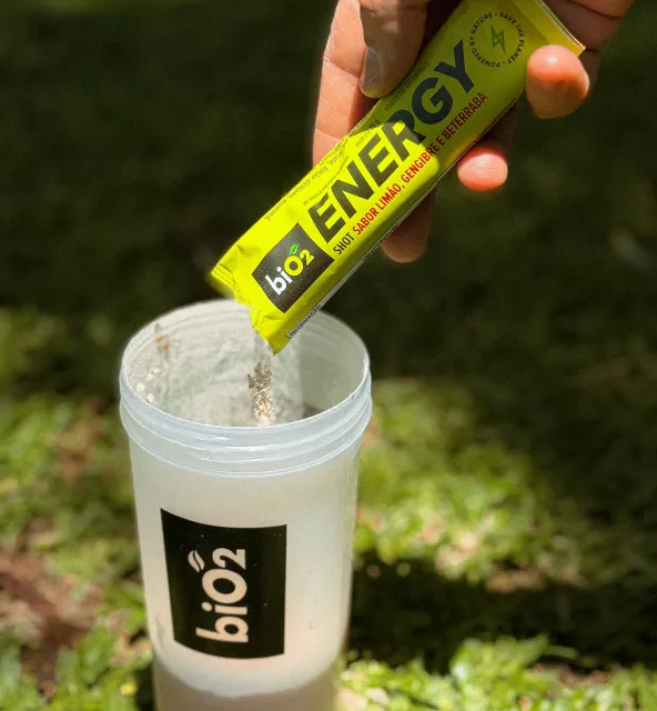 Despejando biO2 Energy Shot Sachê 15 g na coqueteleira em uma grama verde
