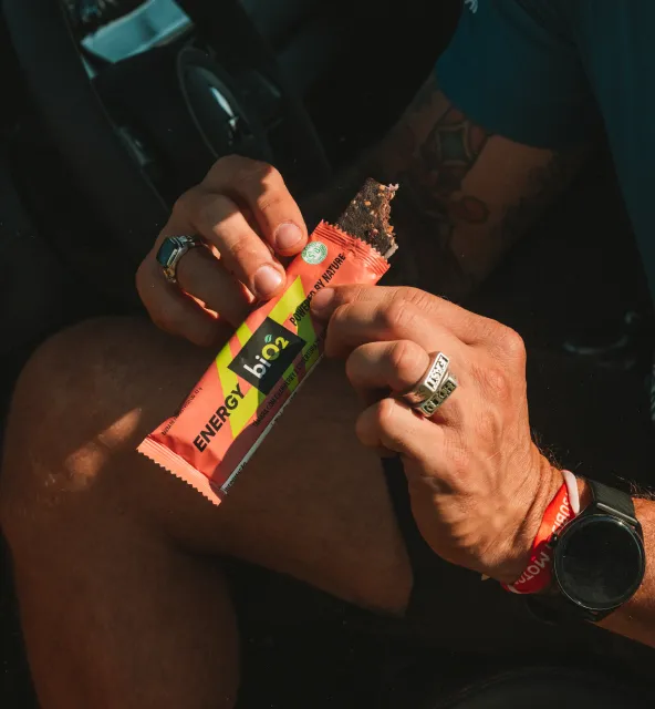 Homem segurando a barra aberta biO2 Energy Bar Framboesa