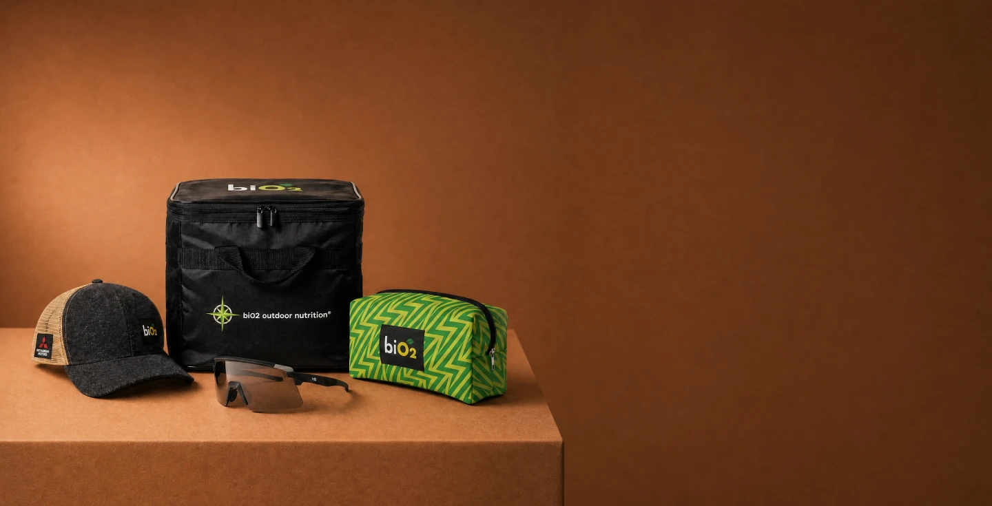 Necessaire, boné, lancheira e óculos biO2 sobre mesa marrom