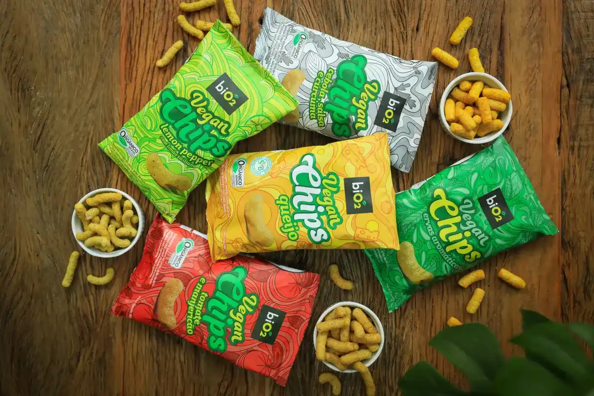 5 salgadinhos biO2 Vegan Chips de diversos sabores em mesa de madeira