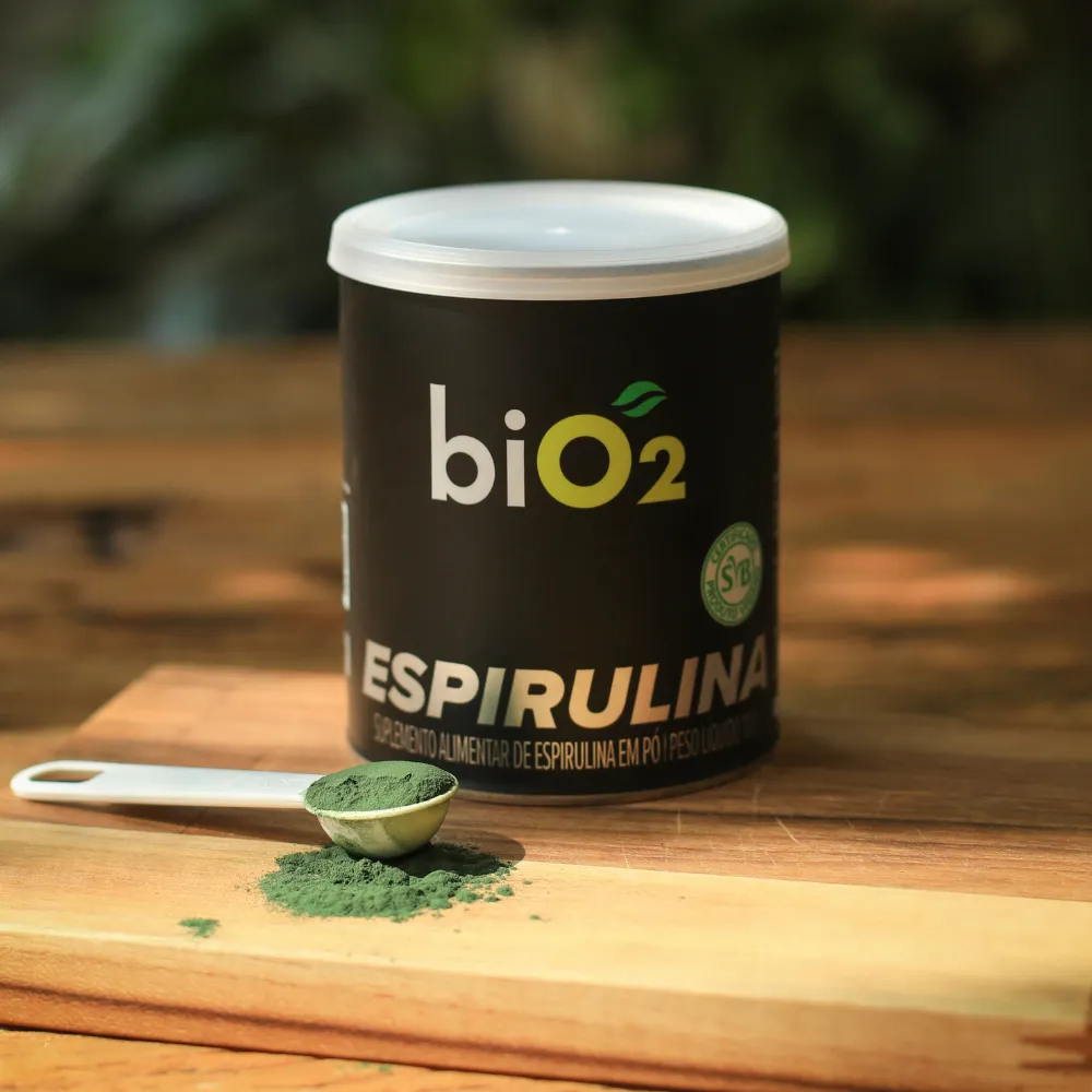 Embalagem de 100 gramas da Espirulina em Pó biO2, vegano e sem glúten, com colher de dosagem do pó verde na frente.