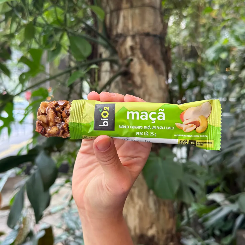 Parte da barra de Castanhas e Frutas biO2, vegana e sem glúetn, sabor Maçã, para fora da embalagem de 25 gramas, exibindo a textura das castanhas.
