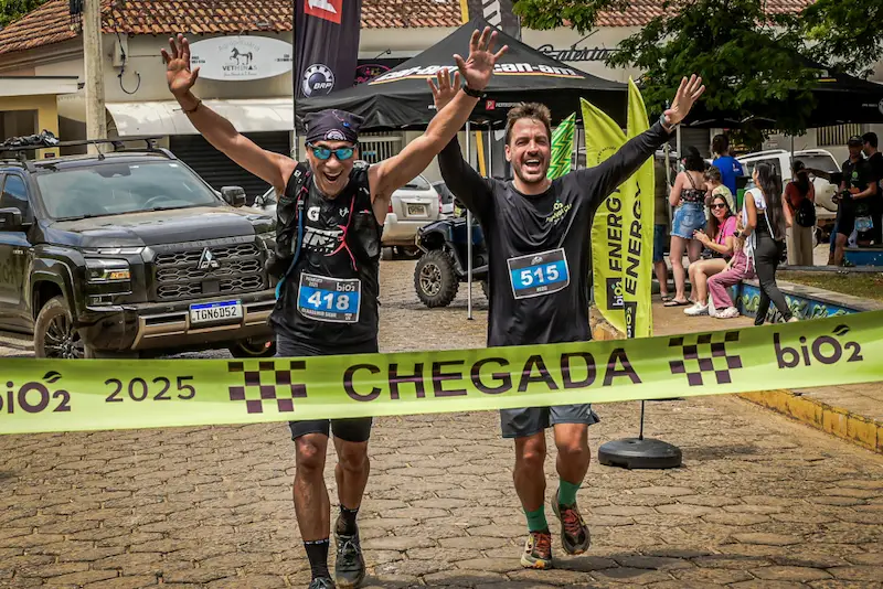 Dois atletas de corrida com sorriso no rosto chegando na linha de chegada da Corrida biO2 de Piranguçu de 2025