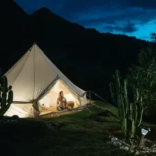 Tenda acesa na Floresta bio2 de noite com montanhas ao fundo